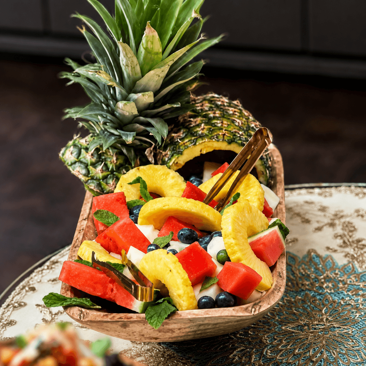 A vibrant bowl of fresh watermelon, pineapple, and blueberries served with a whole pineapple for a retreat gathering