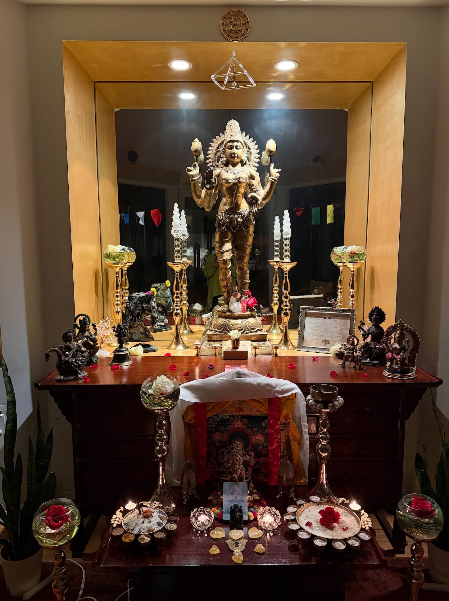 A devotional shrine with a golden deity statue, candles, crystals and offerings prepared for ceremony