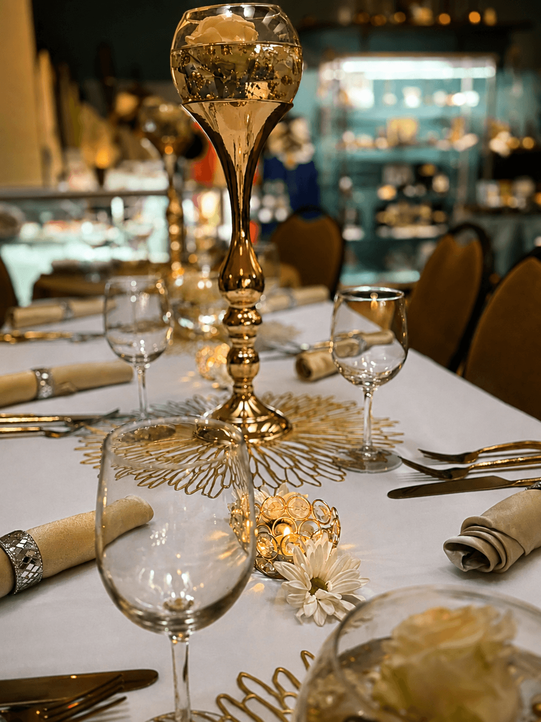 An elegantly set table in the Heart Center's dining hall, gold goblets, crystal candles and fresh flowers