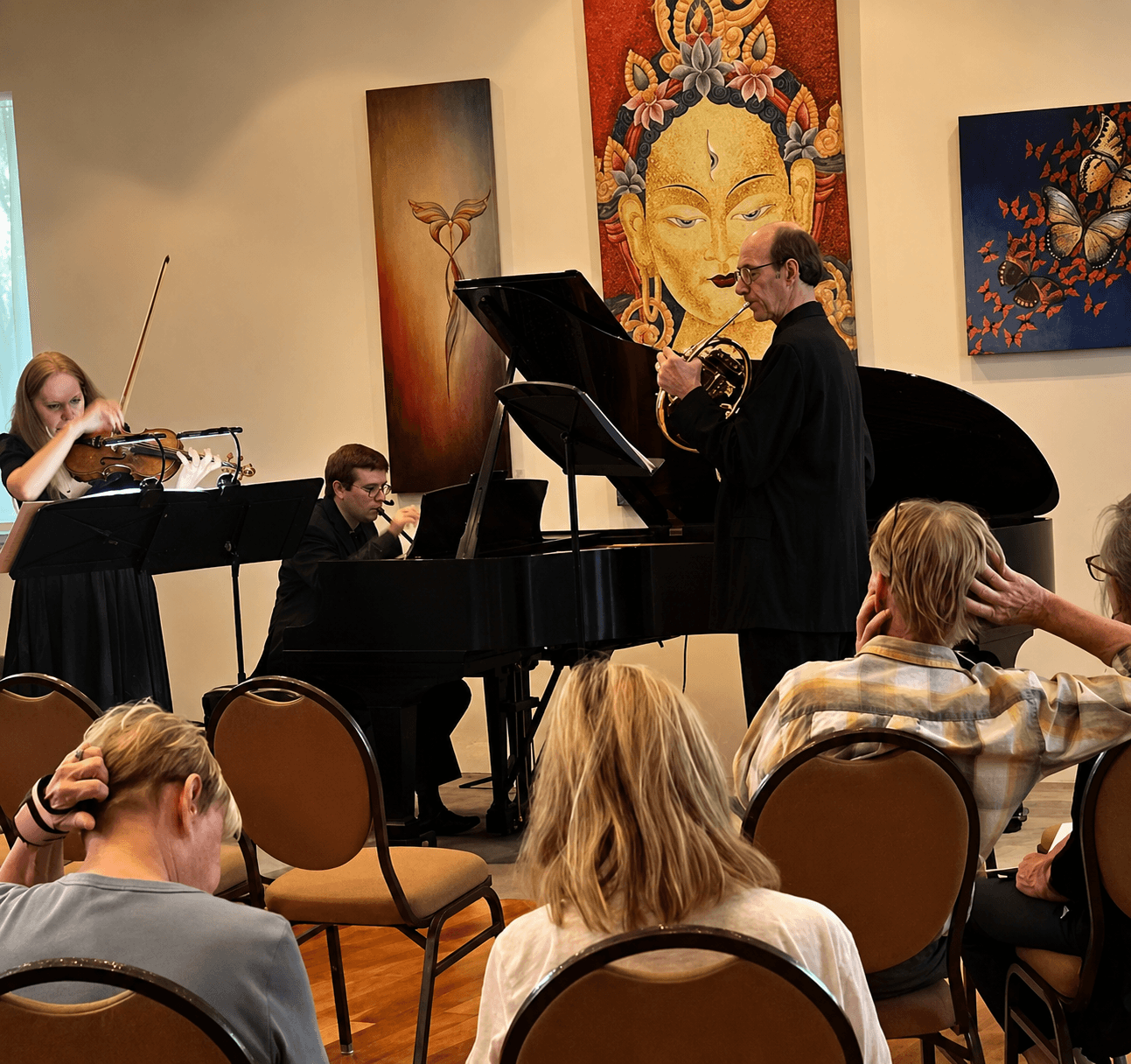 Chamber musicians filling the hall beneath the thangka altar