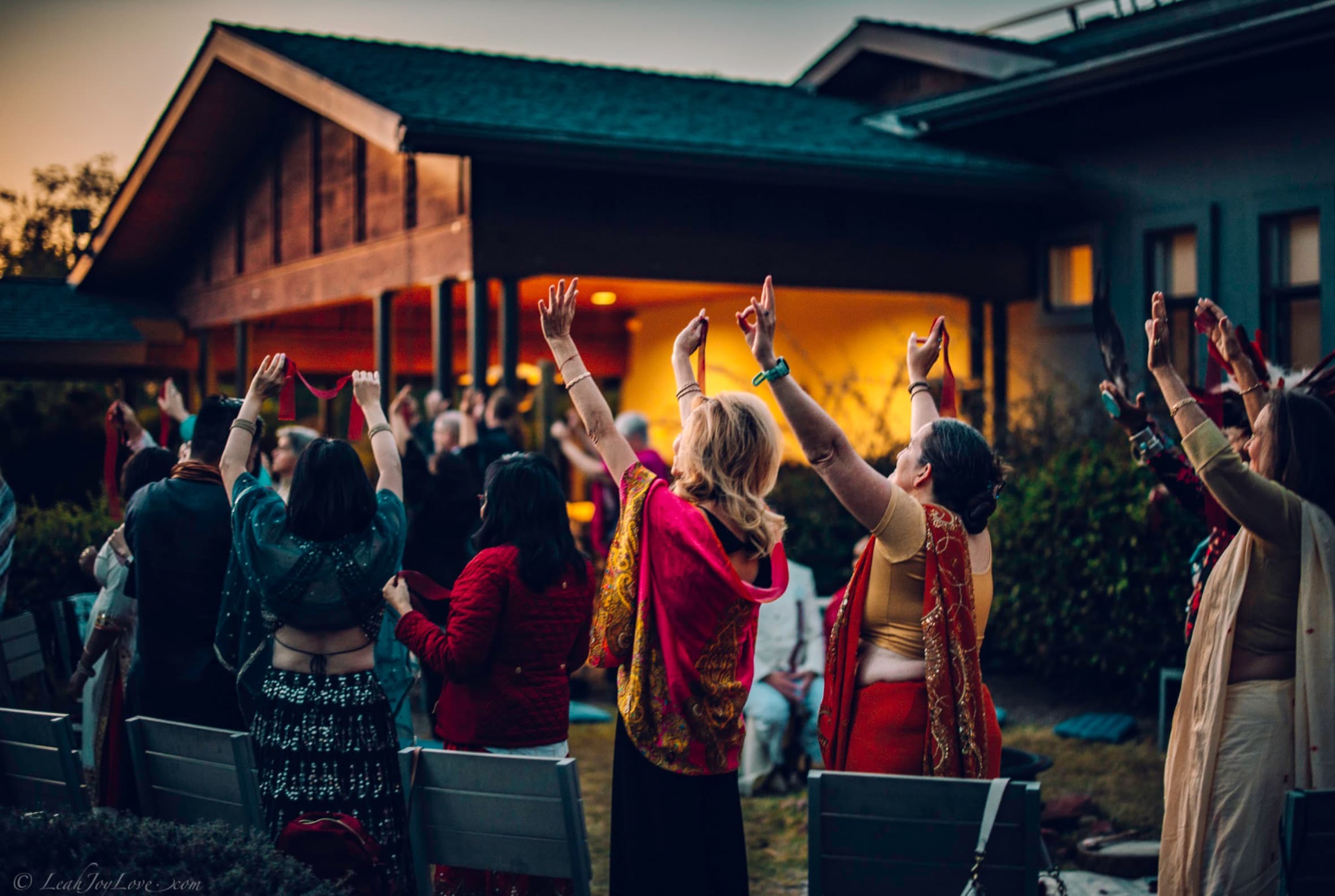 A community with arms raised in ceremony at sunset on the Sedonya grounds