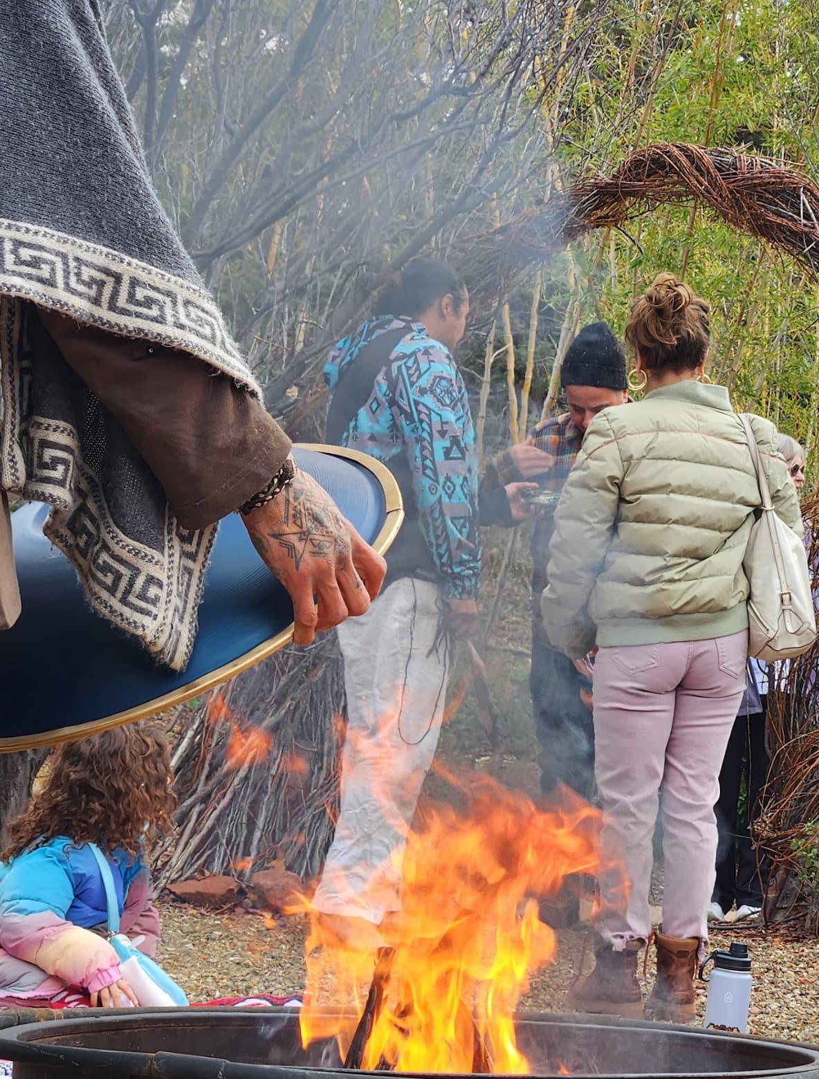 A community gathered in a fire circle at dusk on the Sedonya grounds