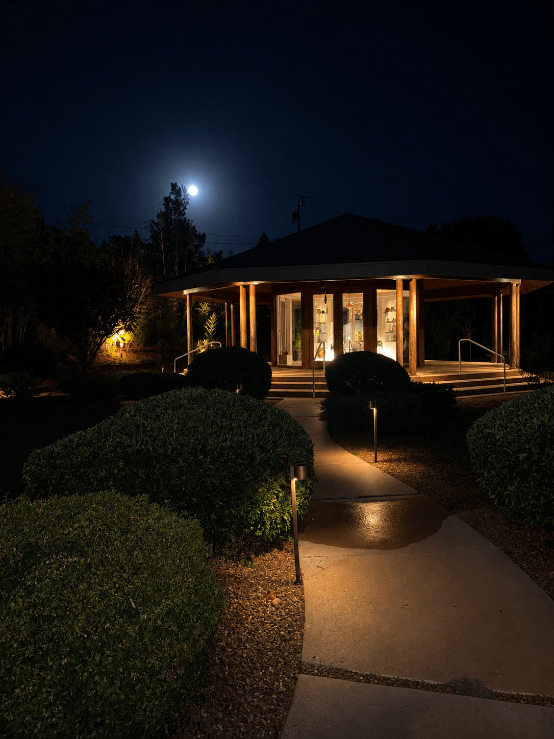 The Temple at night, lit from within, the moon rising above the path that leads to its door